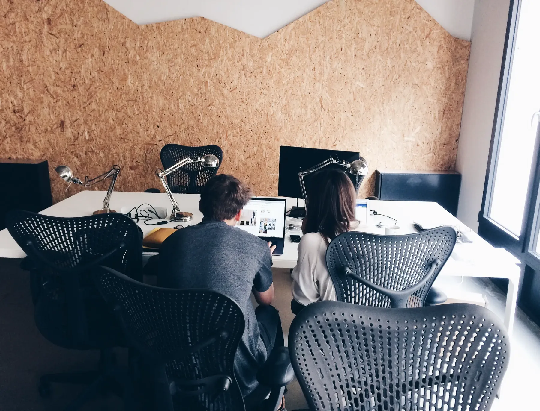 Two people working together at a long digital workspace